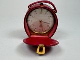a small red clock sitting on top of a red case
