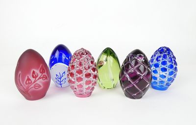 six œufs de Pâques en verre alignés sur une surface blanche