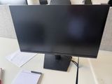 a computer monitor sitting on a desk with a pen and paper