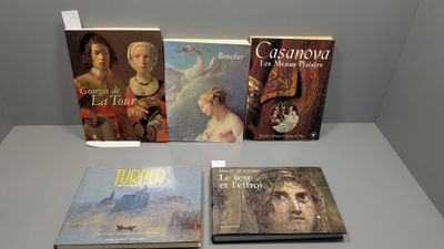 quatre livres exposés sur une table devant un mur gris