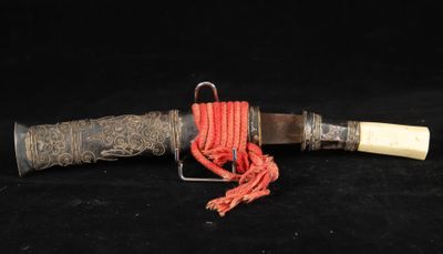an old knife with a handle and a rope on a black background