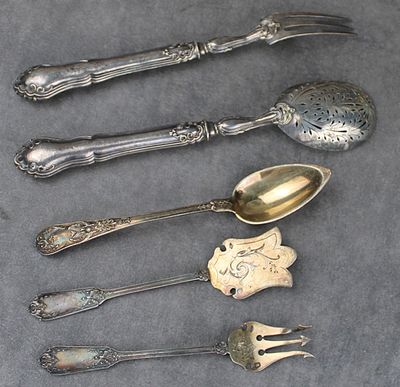 cinq cuillères en argent et une fourchette sont alignées sur une table