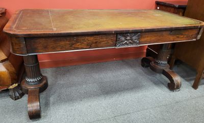 une table en bois recouverte d'un plateau en cuir, avec deux chaises placées en face