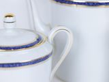 a white tea pot with blue trim and a white tea pot with a gold rim