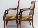 two wooden chairs with striped upholstered seats against a white wall