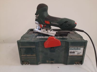 an image of a corded jig saw sitting on top of a tool box