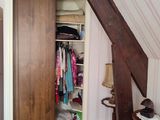 une armoire dans un coin d'une pièce, sur laquelle sont posés des vêtements
