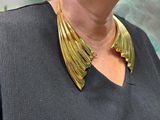 a woman that is wearing a gold necklace and a black shirt