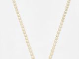 un collier de perles blanches avec un fermoir en or sur fond blanc