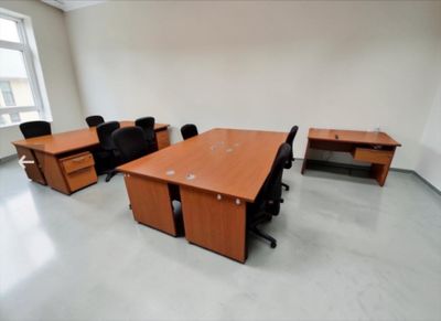 a room with a desk, chairs, and a window