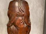 a wooden statue of a man sitting on a glass table