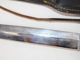 a knife that is laying on a table next to a knife sheath