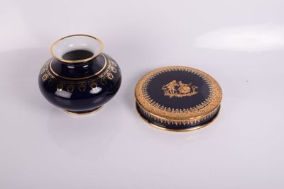 un vase noir et un couvercle doré posés sur une surface blanche