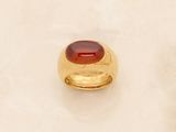 two gold rings with a red stone on top of a white surface