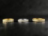 three gold and silver rings on a black surface