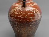 un vase marron portant une inscription, posé sur une table