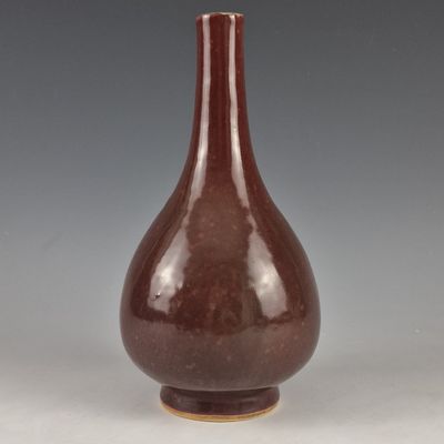 un vieux vase marron posé sur une table près d'un mur gris