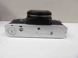 a silver camera with a black lens on a white table