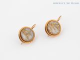 a pair of earrings with gold and white marbles on a white surface