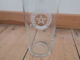 a glass with a pentagram on it sitting on a wooden table