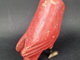 an old red bird figurine sitting on top of a black surface