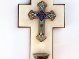 a cross on the wall with a bowl in front of it