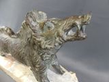 bronze statue of a boar on a rock with its mouth open