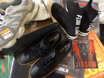 several pairs of black and white shoes and a book on a table