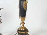 a black and gold vase on a table next to a silver and gold lamp