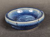 a blue bowl with a fish on it on a table