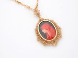 une image représentant un collier en or orné du portrait d'une femme portant un voile rouge