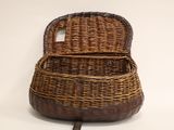 a wicker bag with a handle on a white surface