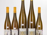 five bottles of wine are lined up on a white surface
