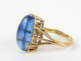 a close up of a gold ring with a blue stone