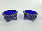 pair of blue glass bowls with silver rims on a white surface
