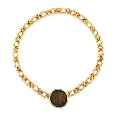 a close up of a gold chain bracelet with a coin on it