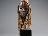 an image of a wooden mask with dreadlocks on a stand