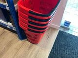 un panier rouge posé par terre à côté d'une étagère bleue