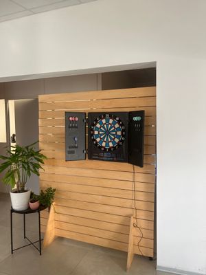 une photo d'un salon avec une télévision et des fléchettes accrochées au mur