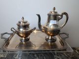 two silver teapots sitting on a tray on a table