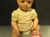 a baby doll sitting on a table with a sheet of paper