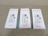 three boxes of silverware sitting on top of a bed next to each other