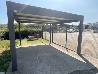 une structure métallique avec un banc au milieu d'un parking