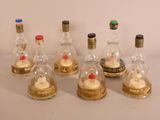 seven bottles of liquor with a cupcake inside of them