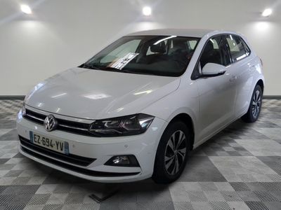 La Volkswagen Polo blanche est garée dans une pièce au sol carrelé.