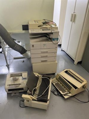 un tas de vieux ordinateurs et une imprimante posés par terre