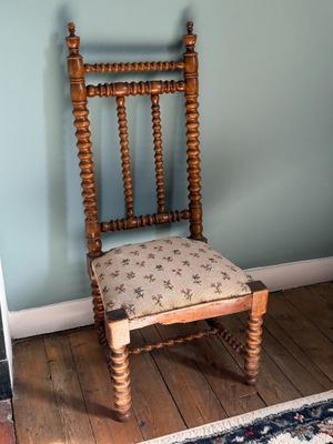 une chaise en bois avec un coussin posé dessus, dans une pièce