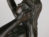 bronze statue of a woman holding her hand up to her face