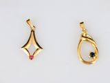 two gold pendants, one with a black diamond and the other with a white diamond