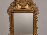 un miroir richement sculpté surmonté d'un vase